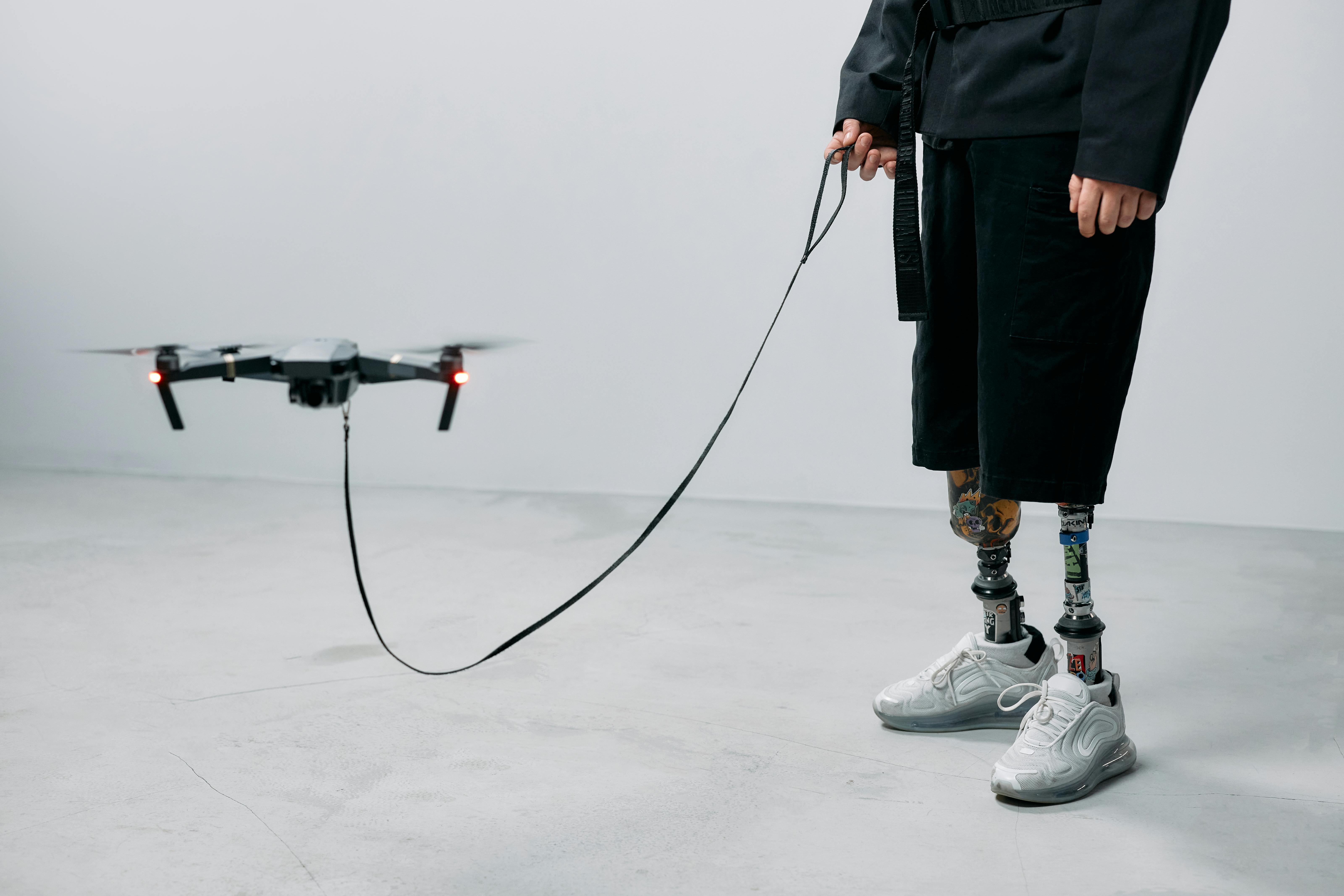 A man with prosthetic legs controls a drone indoors, showcasing innovation and modern technology.