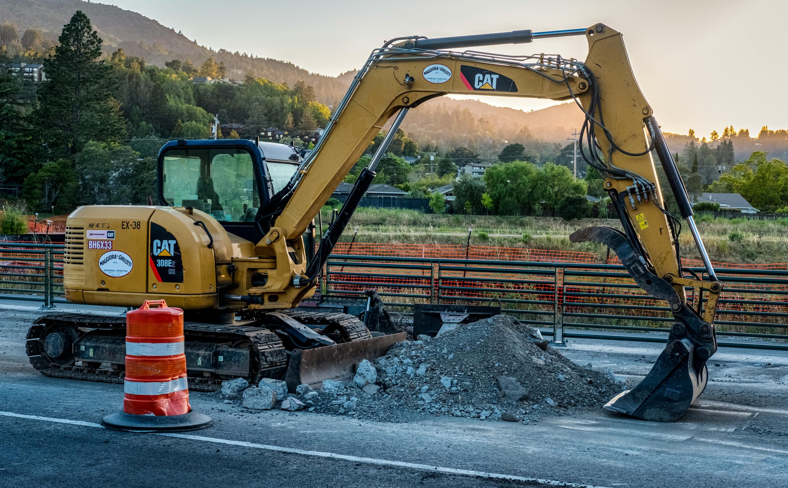 A Caterpillar excavator working on a road construction site with a pile of gravel.